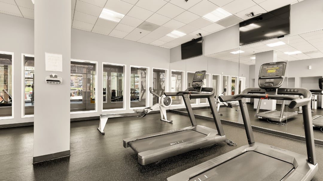 Condo fitness room with treadmills, a rowing machine, and mirrored walls.