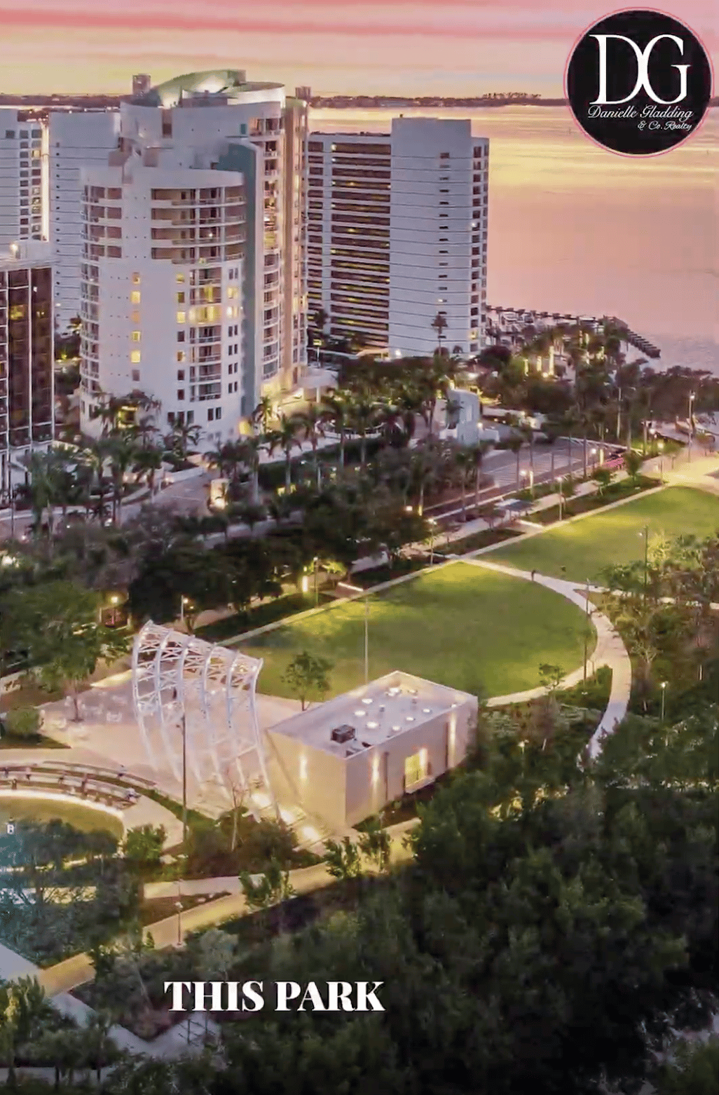 Aerial view of The Bay Park beside Sarasota Bay at dusk, with waterfront towers and winding paths.