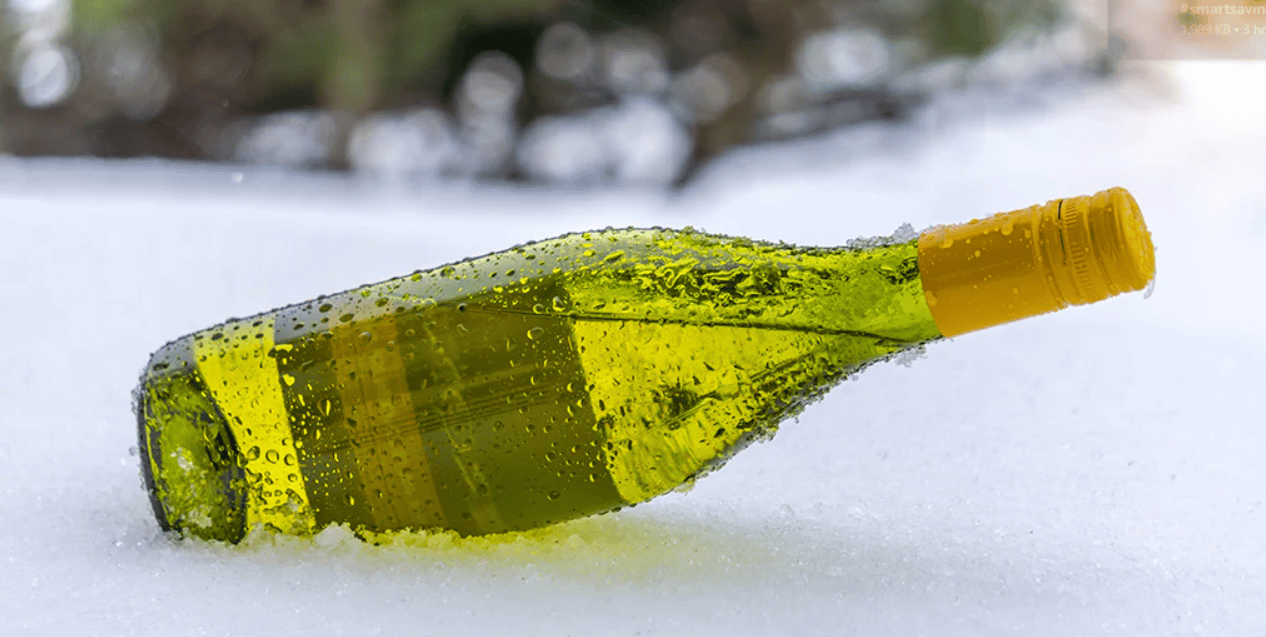A chilled white wine bottle lying in snow.