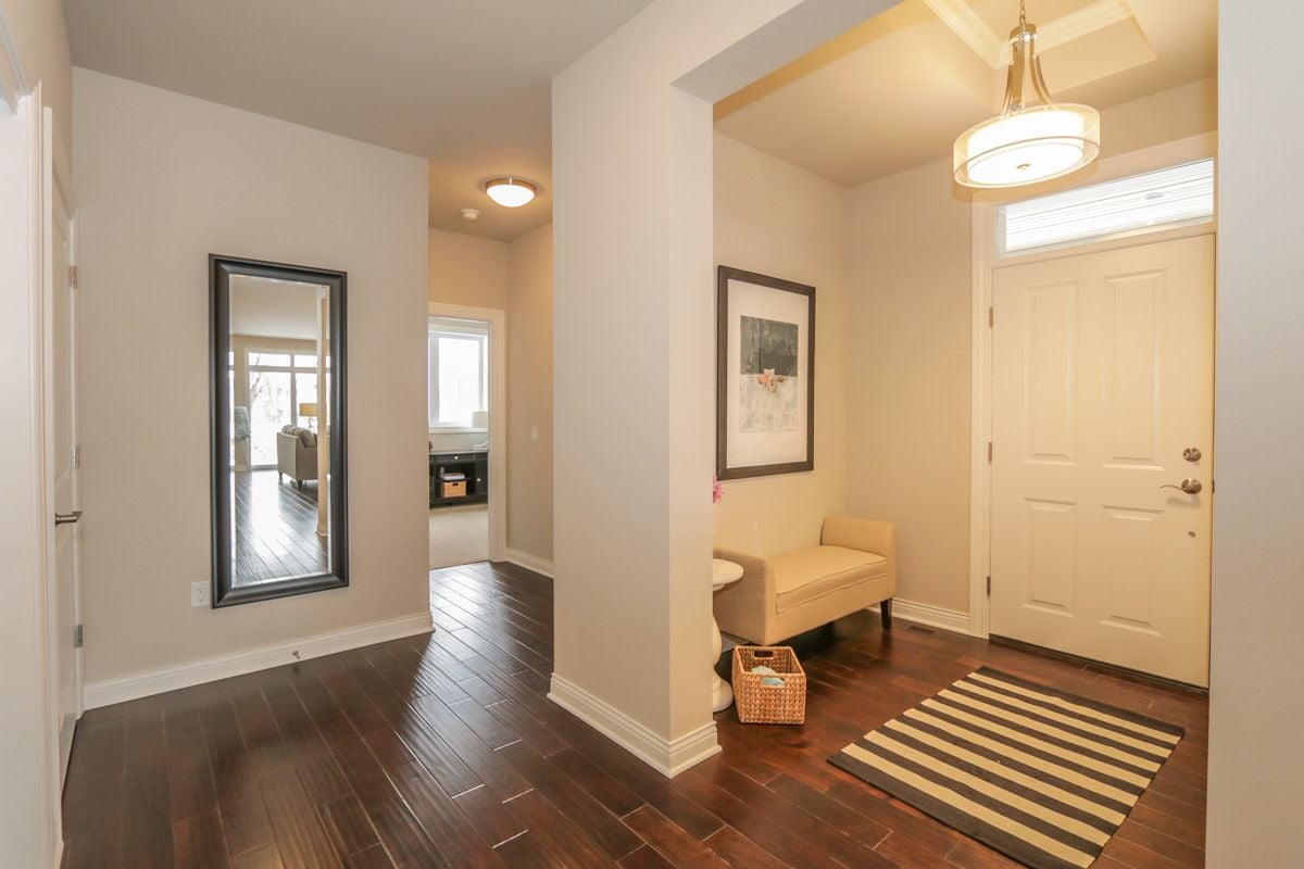 Home entryway with dark hardwood floors, a striped rug, and a white front door.