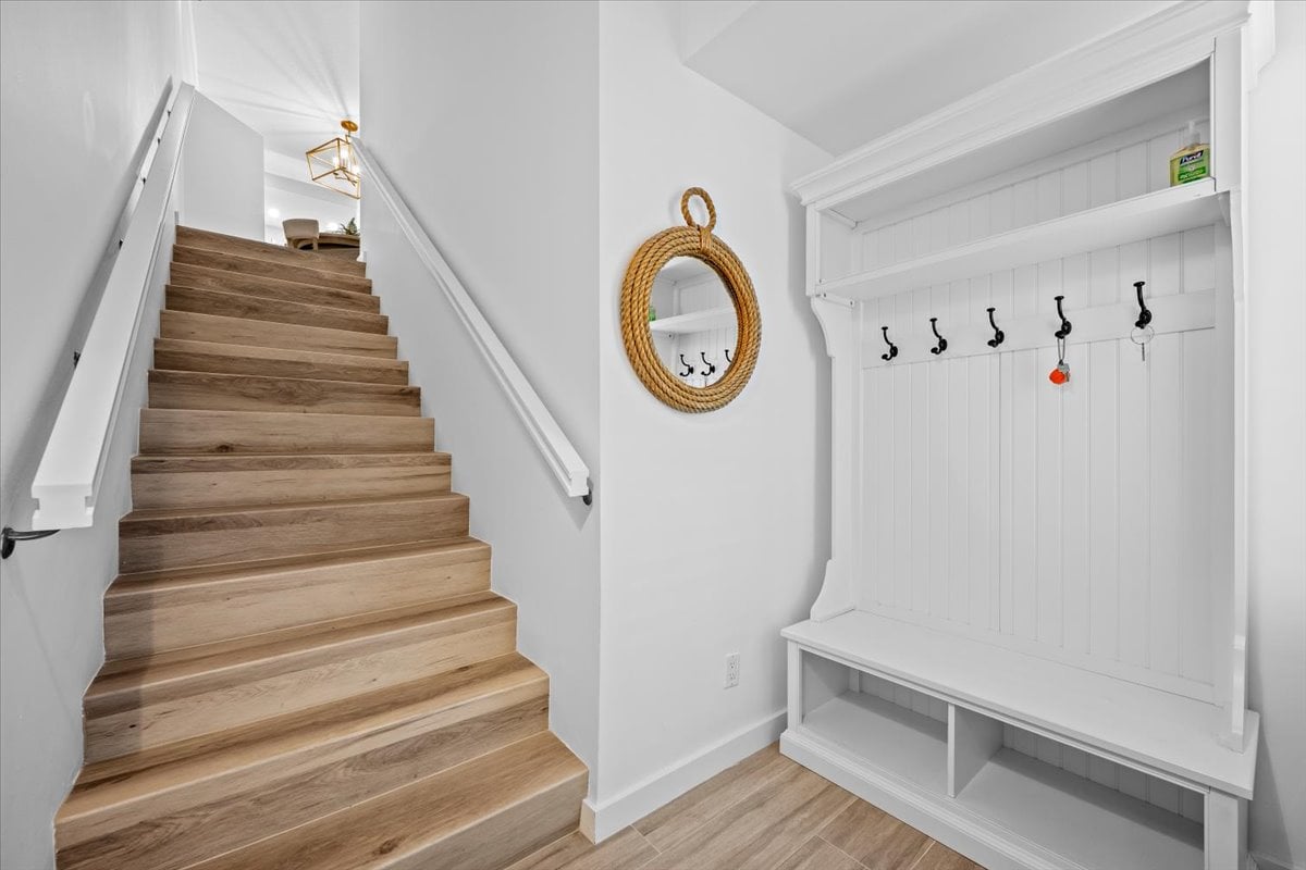 Condominium entryway with a wood staircase and built-in bench with coat hooks.