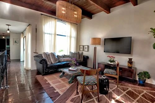 Living room with a leather sofa, patterned rugs, and a vaulted wood ceiling.