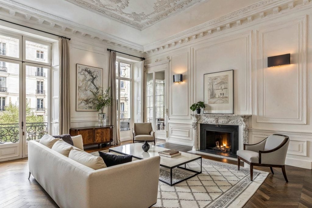 Living room with ornate moldings, tall windows, a marble fireplace, and herringbone wood floors.