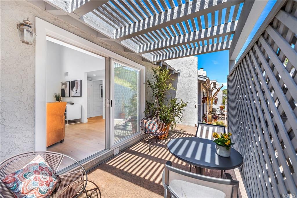 Furnished patio with a slatted pergola, outdoor seating, and sliding glass doors.