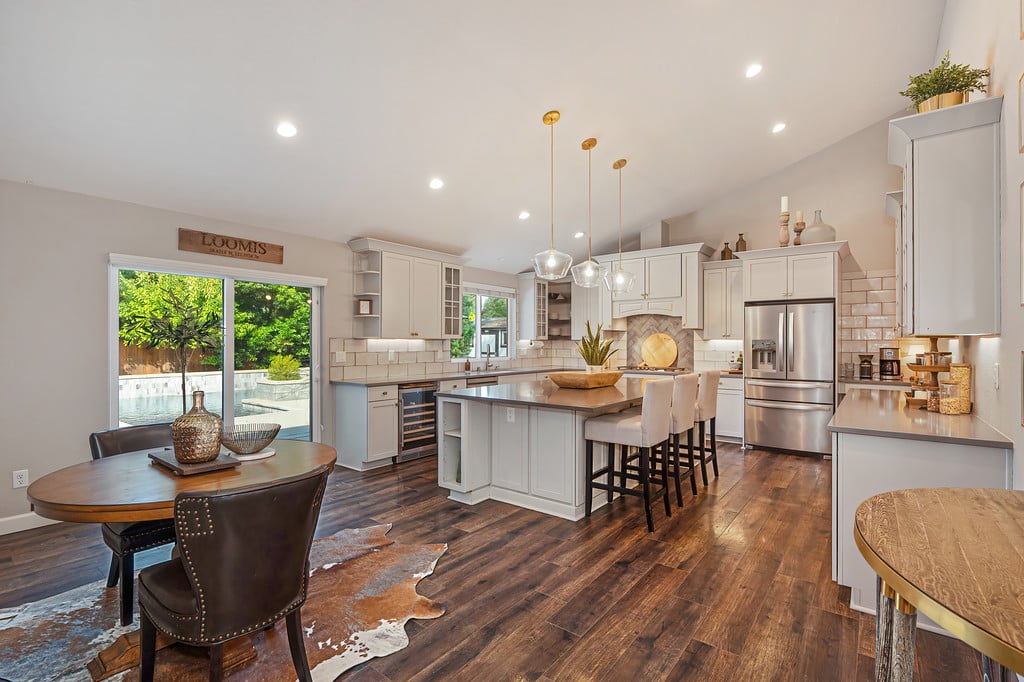 Open-plan kitchen with a large island, dining area, and pool visible through sliding glass doors.