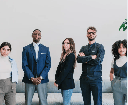 Five adults in business-casual clothing standing together as a group.