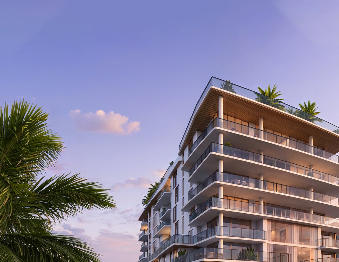 Modern condominium with glass balconies and a wood-toned roof, framed by palm trees at sunset.