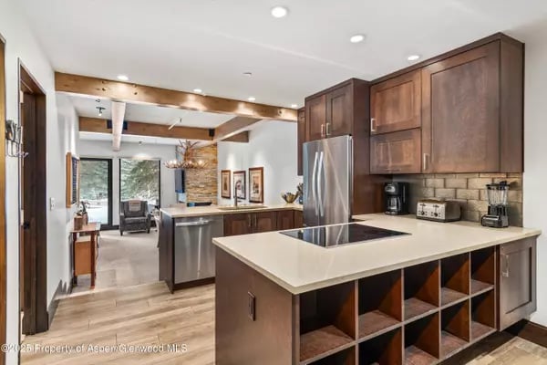Kitchen with a large cooktop island, dark wood cabinetry, and stainless steel appliances.