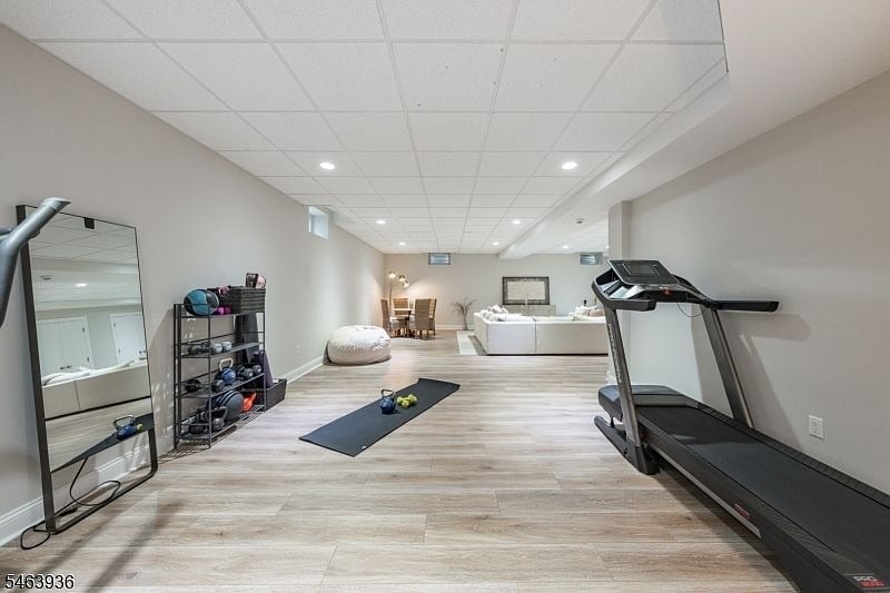 Finished basement gym with treadmill, free weights, yoga mat, and adjoining seating area.