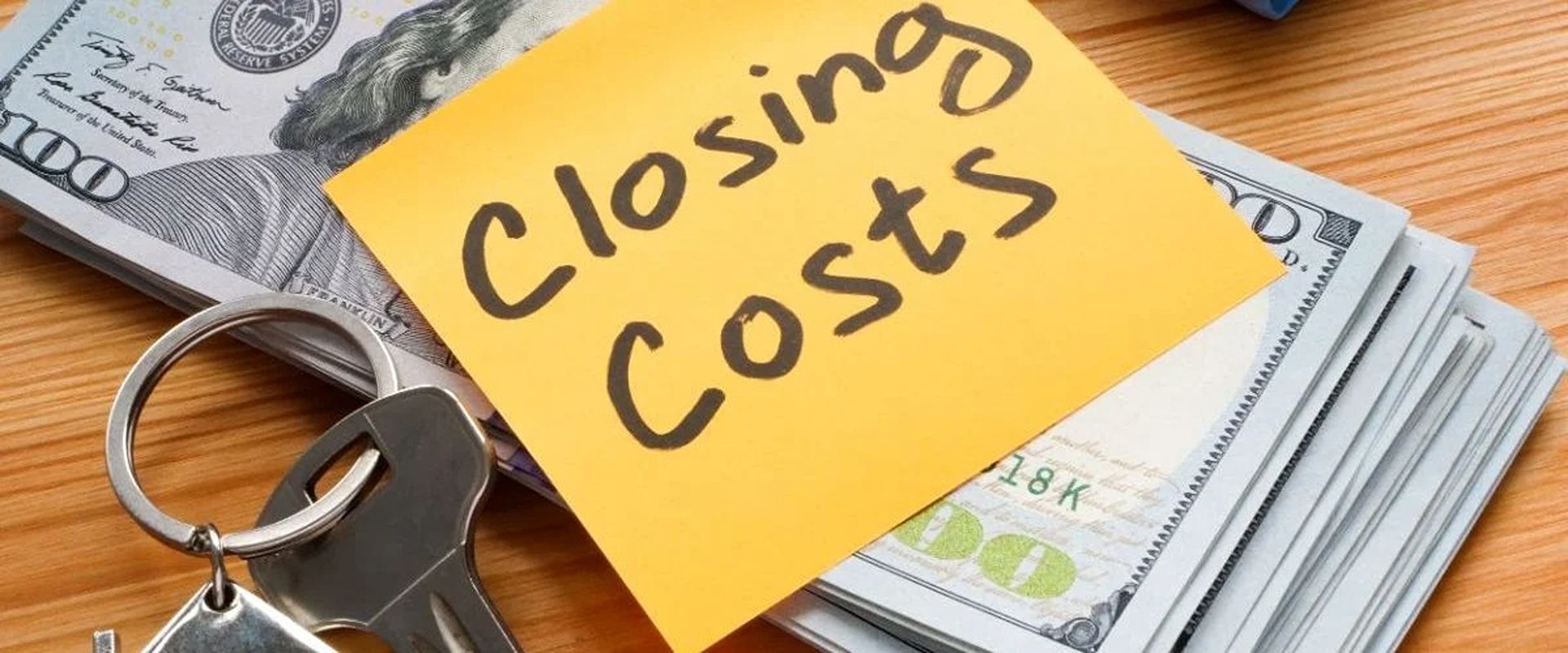A “Closing Costs” note, house keys, and a stack of $100 bills.