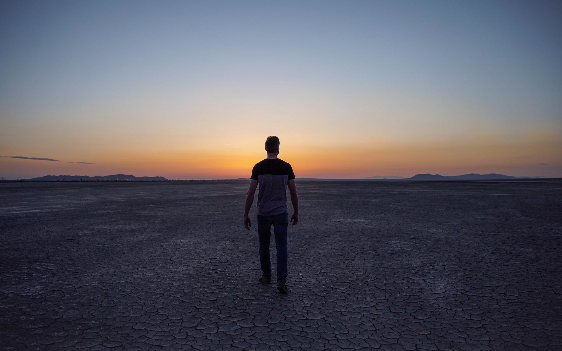 Person standing on a cracked dry lakebed at sunset near Adelanto, photographed in 2017