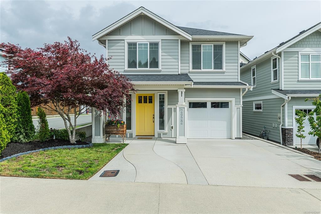 Two-story gray house with a yellow front door, attached garage, and red-leaved tree in the front yard.