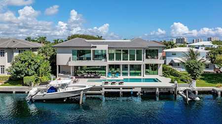 Modern waterfront home with a pool, dock, and boats along the canal.