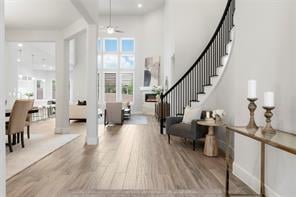 Open-plan living and dining area with light wood floors and a curved staircase.