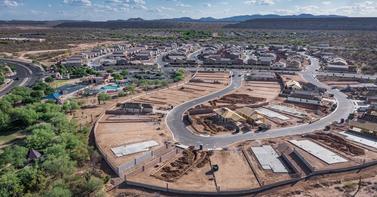 An aerial view of a housing development with one loop of road under construction with numerous house lots.