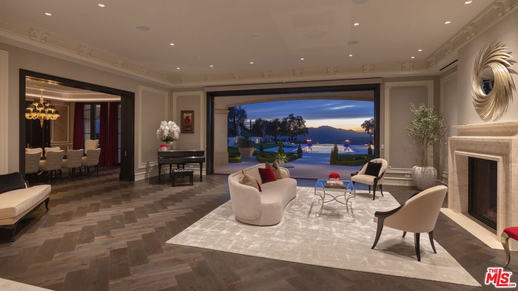 Furnished living room opening to a pool and mountain views at dusk.