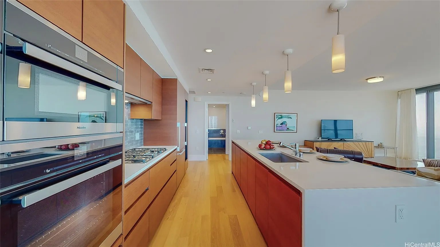 Modern open-plan kitchen with warm wood cabinetry, built-in appliances, and a large white island.