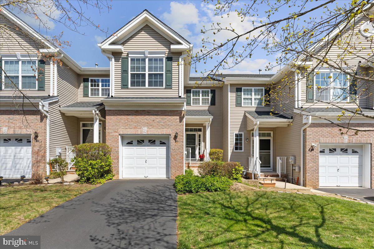 Townhouse exterior with brick accents, green shutters, and an attached garage.