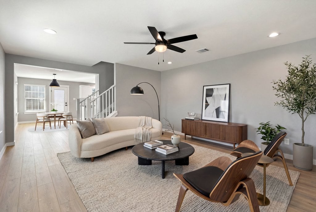 Staged living room with a cream sofa, wood chairs, and an adjoining dining area.