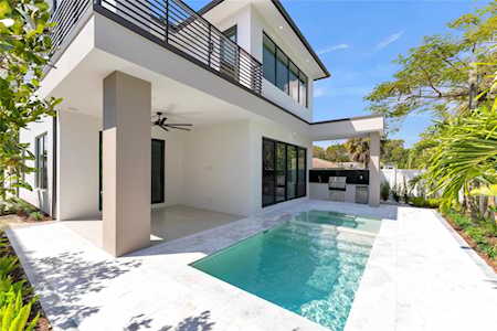 Modern white home with an upper balcony and a narrow pool beside the covered patio.