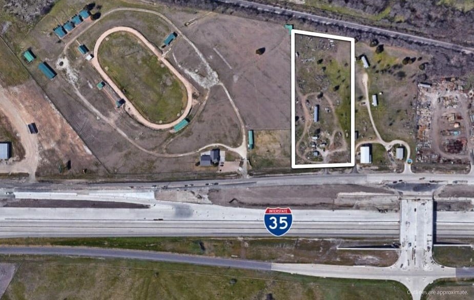 Aerial view of an outlined commercial parcel beside Interstate 35 and an oval track.