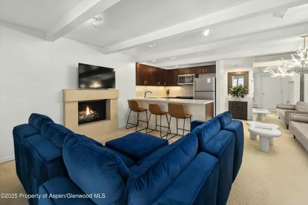 Open-plan living room with a blue sectional, fireplace, and kitchen island with bar stools.