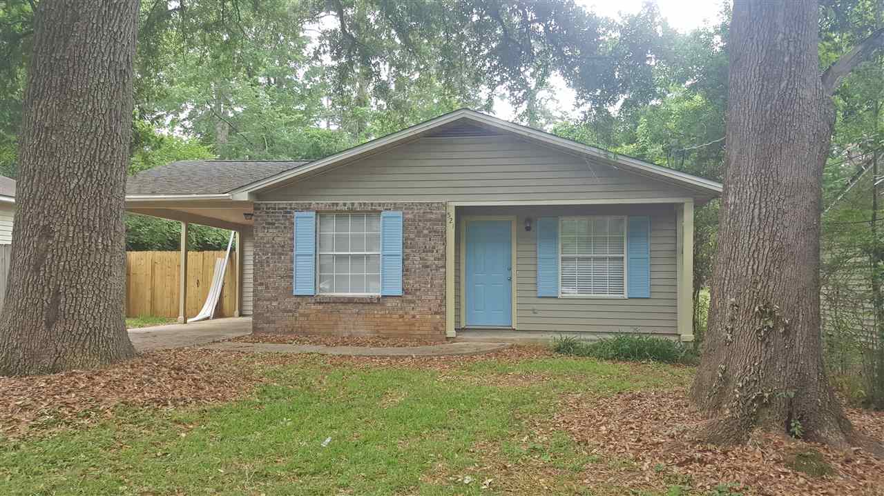 A small house featuring blue shutters, surrounded by a well-maintained yard.