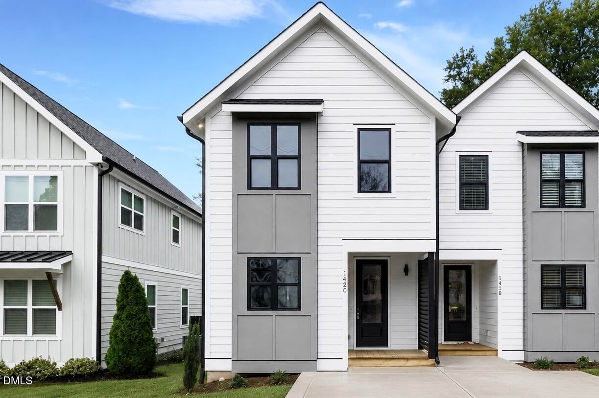 Front exterior of 1420 Joe Louis Avenue, a contemporary white townhome featuring black windows, a covered front porch, and modern architectural details in Raleigh, North Carolina.