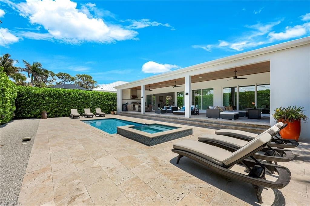 Modern home patio with a swimming pool, raised spa, and lounge chairs.