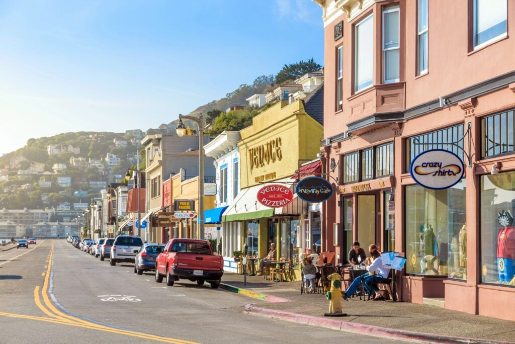 Waterfront street in Sausalito, California, with local restaurants, sidewalk dining, and hillside homes in Marin County