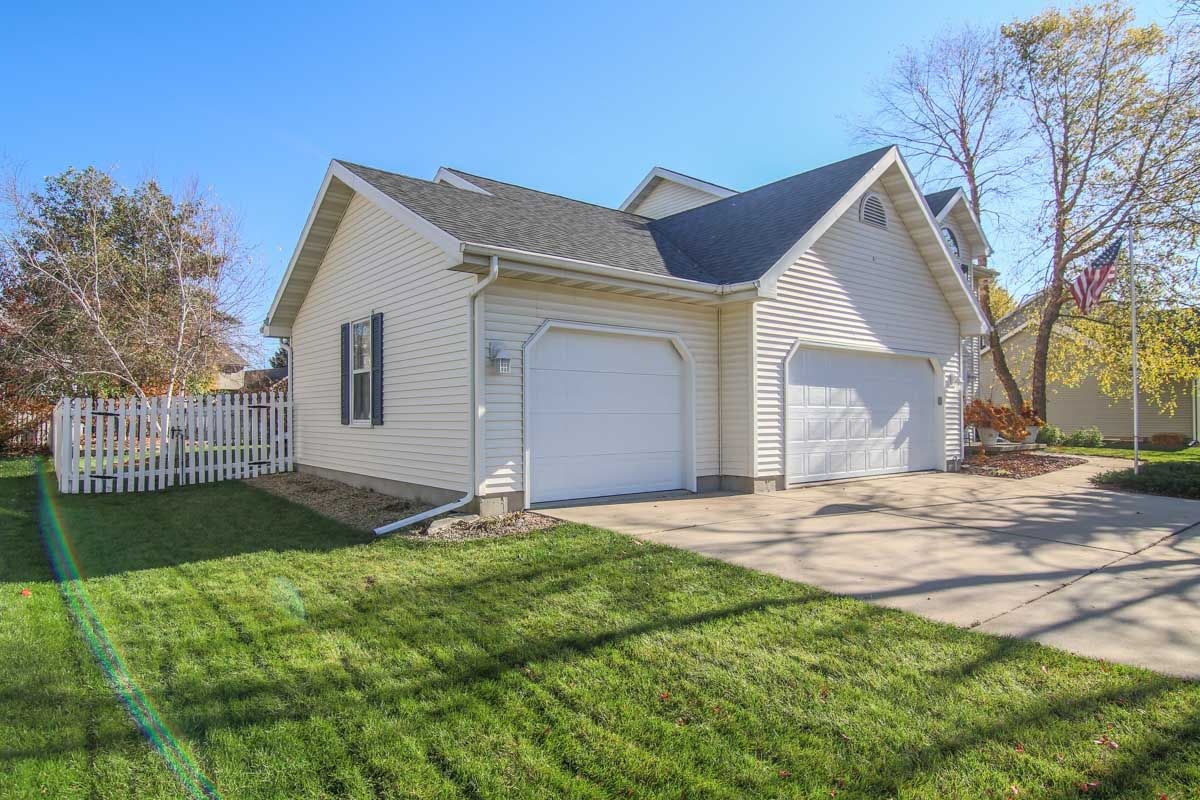 Custom-built colonial home with two garage doors, a broad driveway, and a white picket fence.