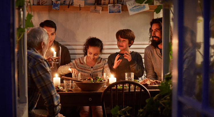 A group of individuals gathered around a table illuminated by soft candlelight, creating a warm and inviting atmosphere.