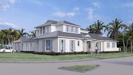 White two-story home with gray roofs and palm trees behind it, shown from the street corner.