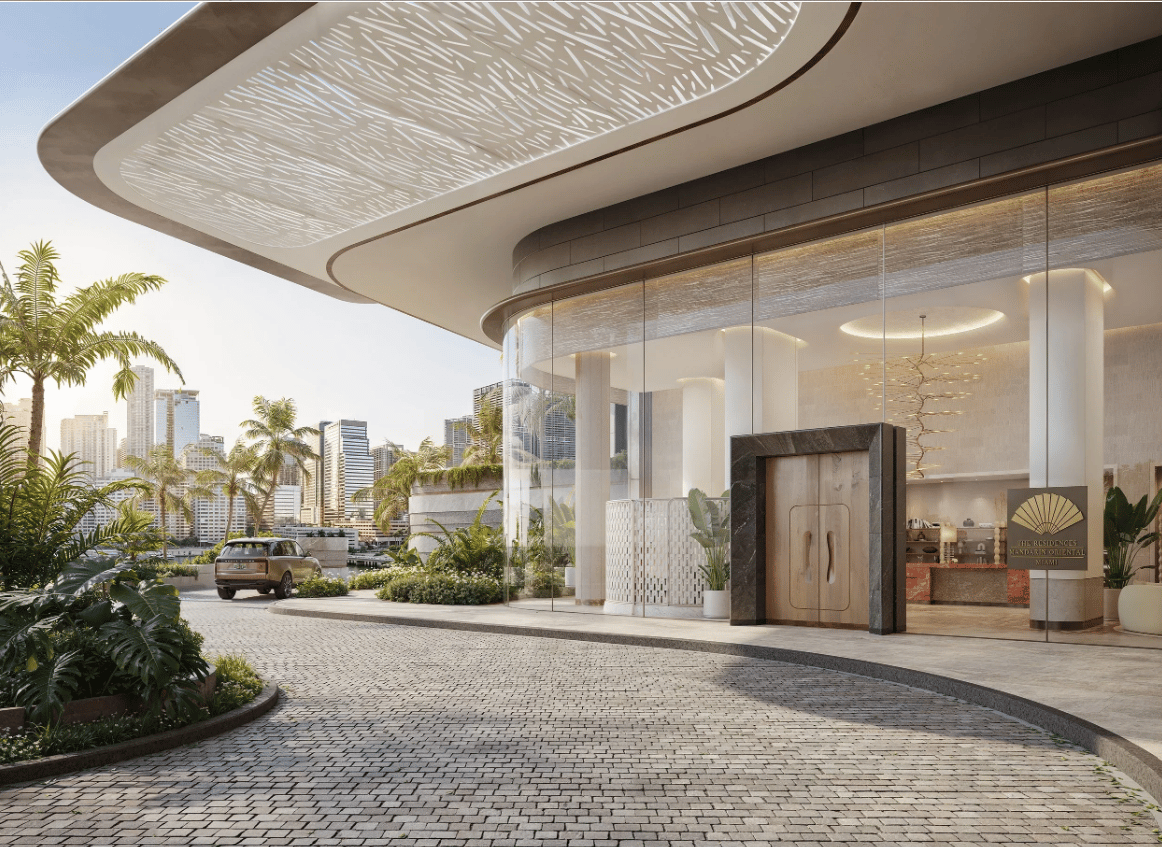 The Residences at Mandarin Oriental Miami entrance beneath a sweeping canopy, with tropical landscaping and the city skyline.