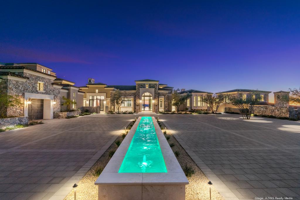 Luxurious modern mansion with a long illuminated water feature at dusk.