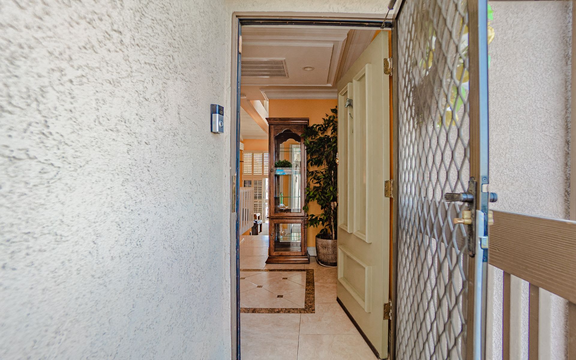 Open front entrance with a metal security door and tiled foyer beyond.