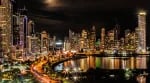 Illuminated city skyline reflected on the waterfront at night.