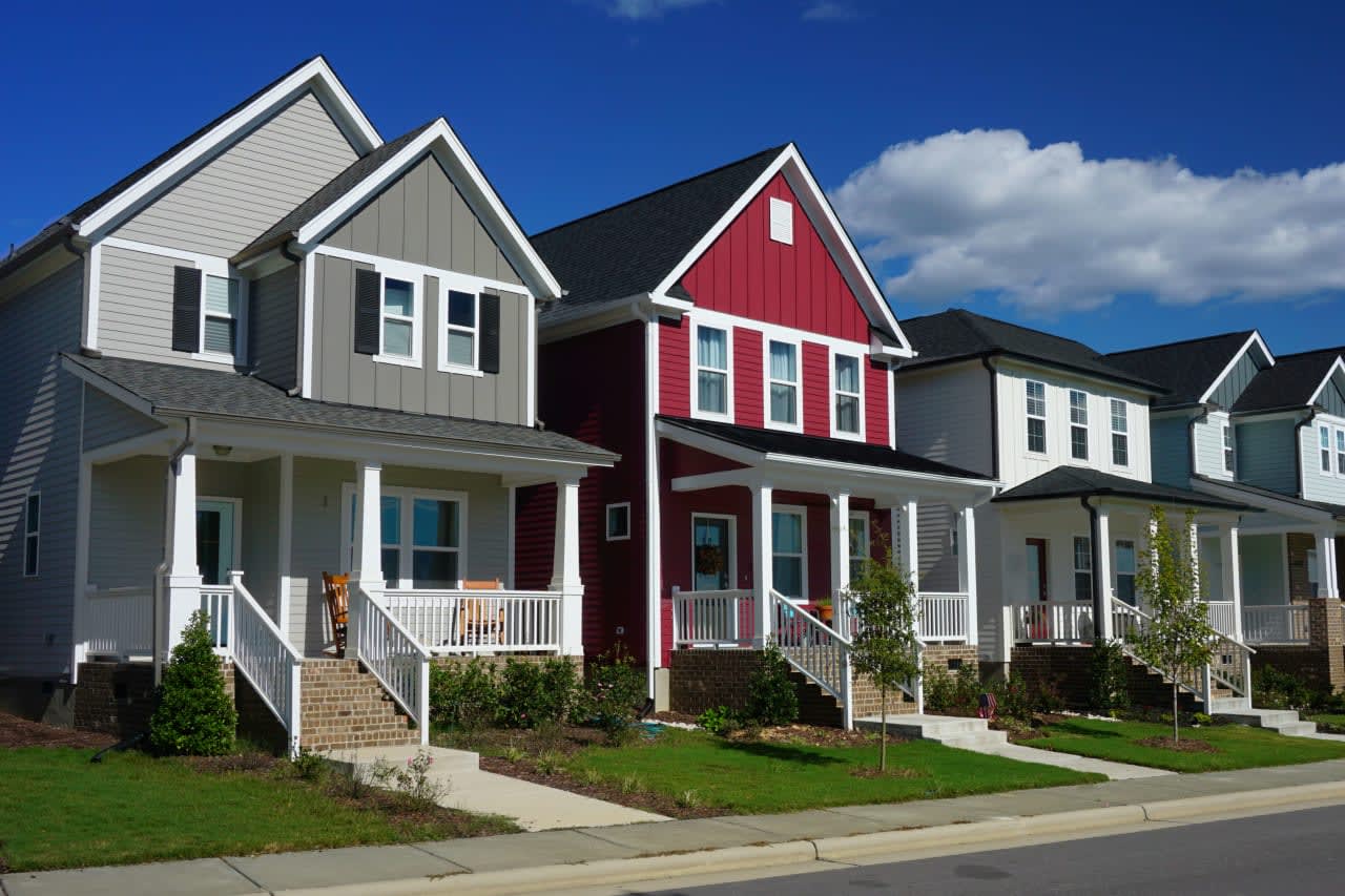 A row of new, colorful townhomes with welcoming porches symbolizing modern and stylish suburban living.