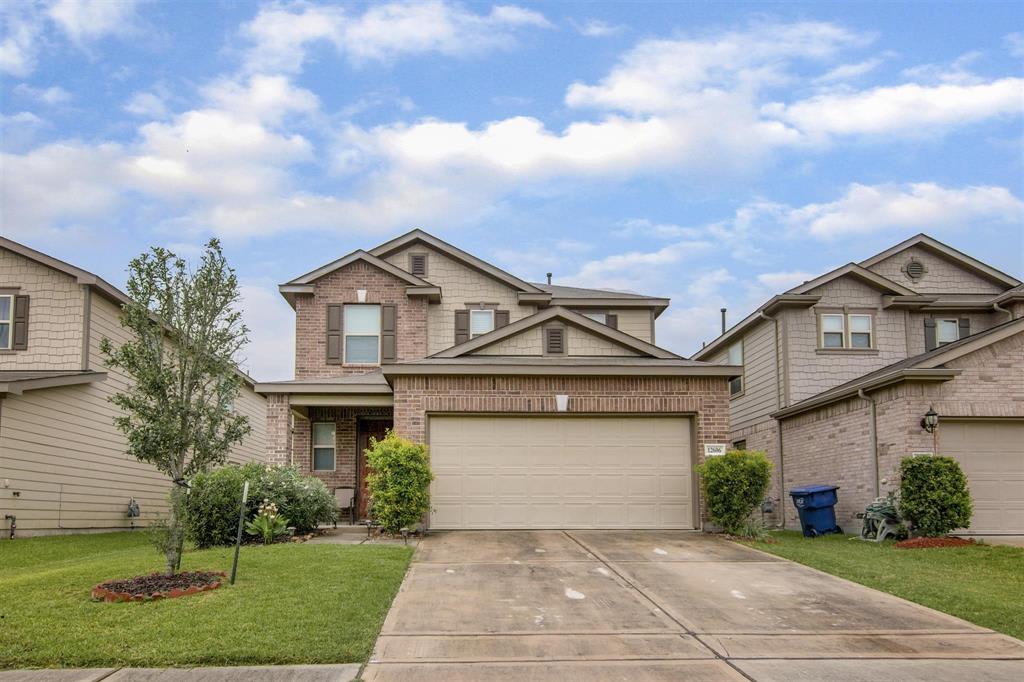 Two-story brick house with a wide double garage, driveway, and front lawn.