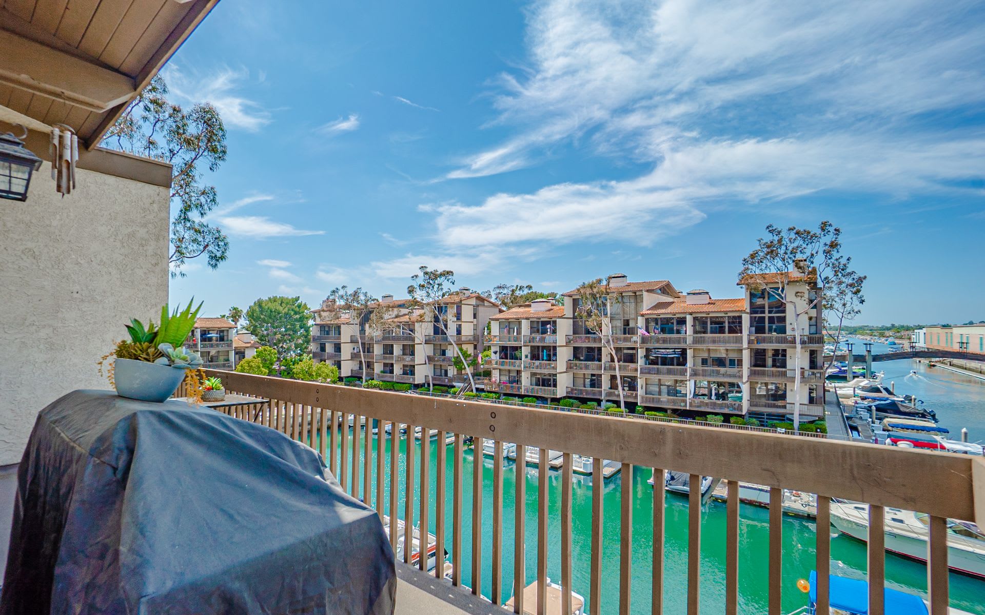 Condo balcony overlooking a marina canal, boats, and waterfront buildings.