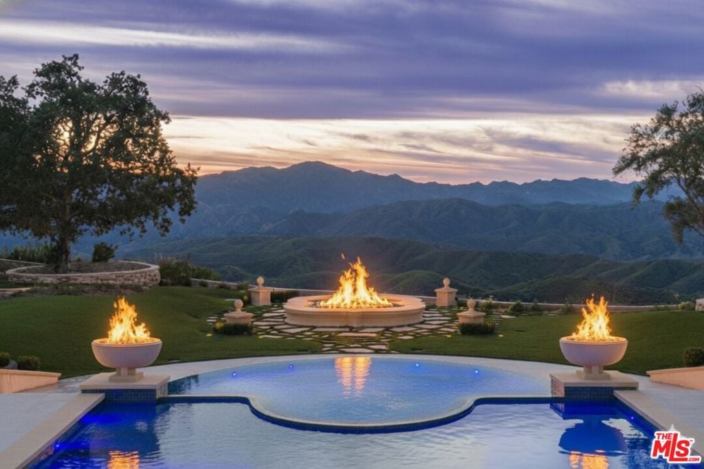 Pool and fire features overlook mountain ridges at dusk.