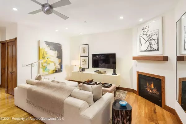 Furnished living room with a cream sectional, fireplace, and wall-mounted television.