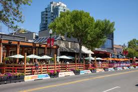 This image captures the vibrant energy of Calgary's 17th Avenue SW, a sun-soaked hotspot where colorful patios line the street, offering prime people-watching, lively dining, and the essence of summer 2025.