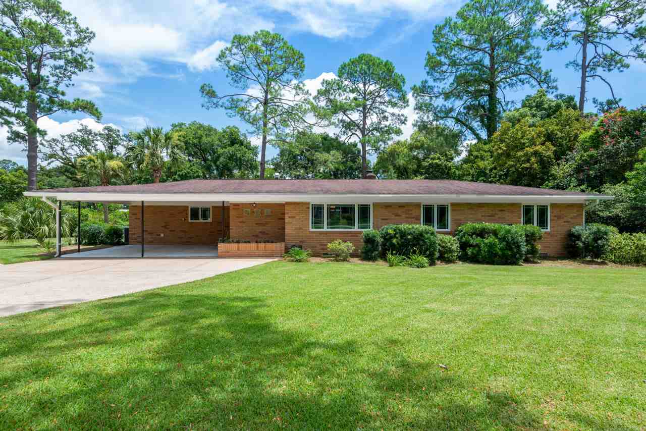 A brick home surrounded by lush green grass and trees, creating a serene and inviting outdoor environment.