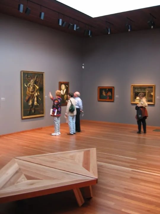 Interior gallery view showing visitors engaging with American art collection, with natural light streaming through the museum's distinctive architectural features.