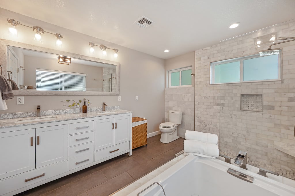 Bathroom with a white double vanity, soaking tub, and marble-tiled walk-in shower.