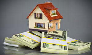 Model house perched on bundled U.S. dollar bills