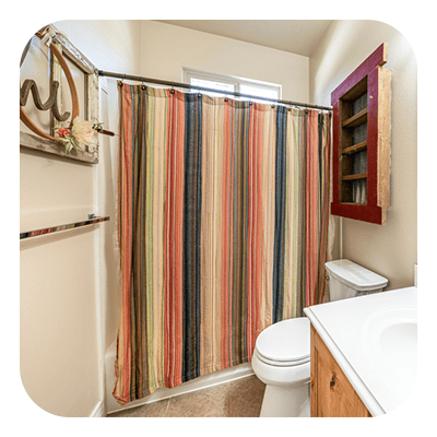 Bathroom with a colorful striped shower curtain, white toilet, and wood vanity.