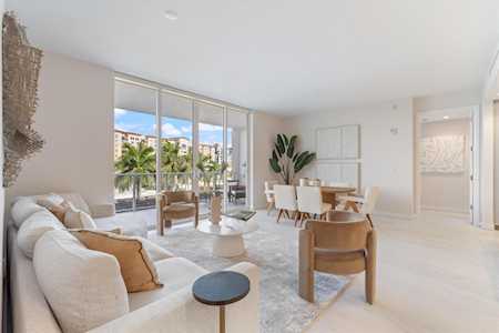 Open-plan living and dining room with a white sectional and large balcony-facing windows.
