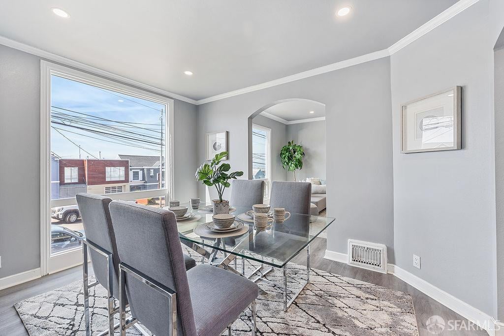 Dining room with a glass-top table, gray chairs, and a large street-facing window.